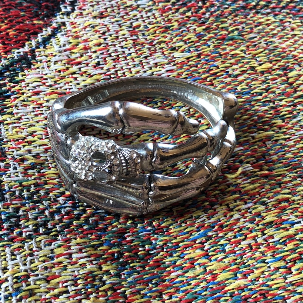 Bejeweled skull on skeleton hand bracelet
